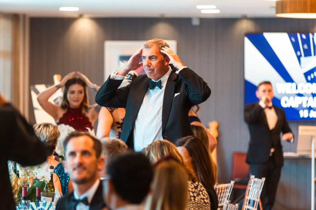 Guests in black tie playing a heads or tails fundraising game while the host runs it from the stage Guests in black tie playing a heads or tails fundraising game while the host runs it from the stage