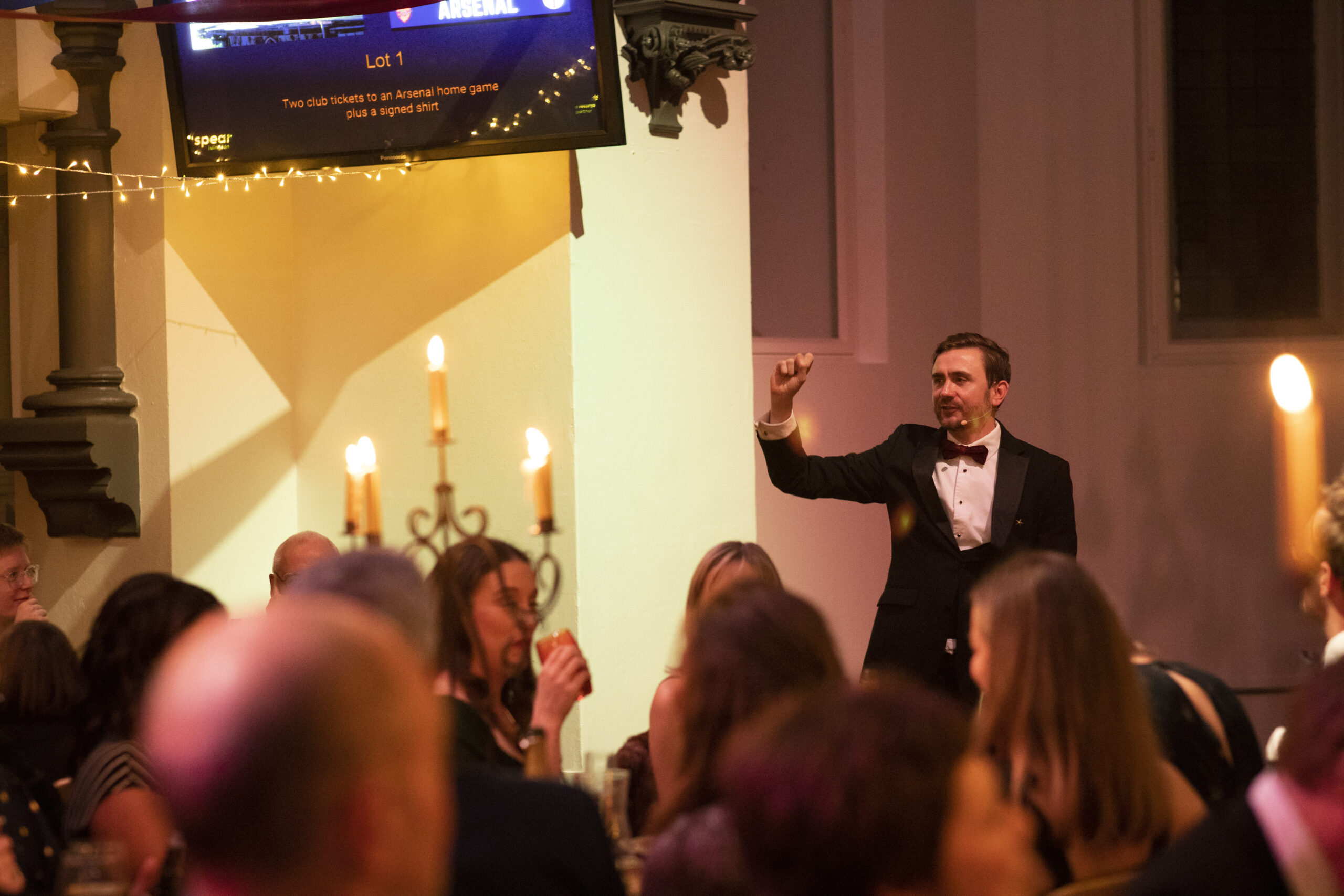 Auctioneer taking a bid as a signed Arsenal shirt and match tickets lot shows on the screen behind him