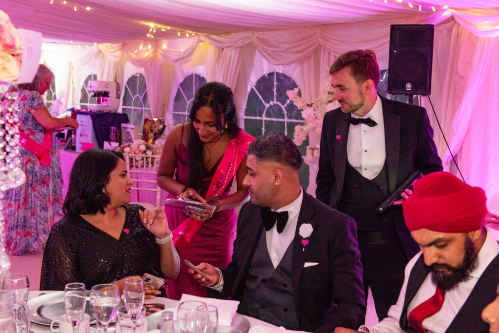 Charity auctioneer in black tie talking with guests at a marquee fundraising event Charity auctioneer in black tie talking with guests at a marquee fundraising event