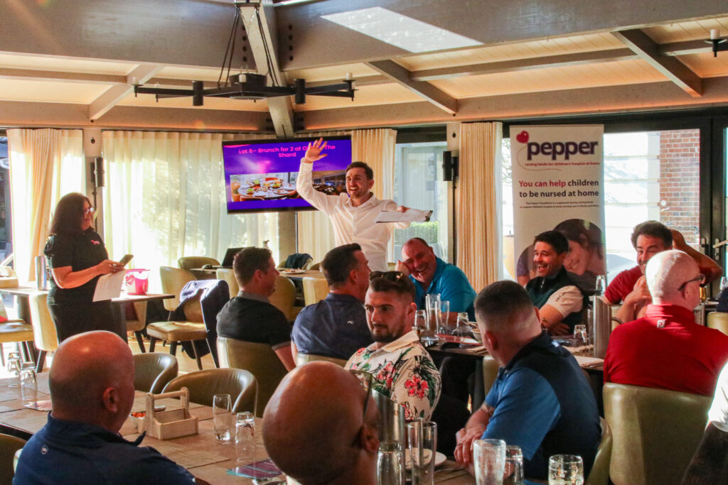 Charity auctioneer in a white shirt hosting a lot at a daytime charity sports lunch Charity auctioneer in a white shirt hosting a lot at a daytime charity sports lunch