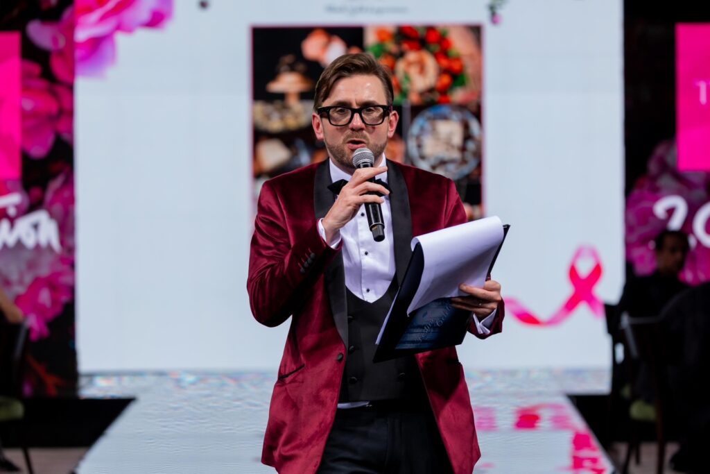 Charity auctioneer reading the next lot from his notes on stage at a charity ball Charity auctioneer reading the next lot from his notes on stage at a charity ball