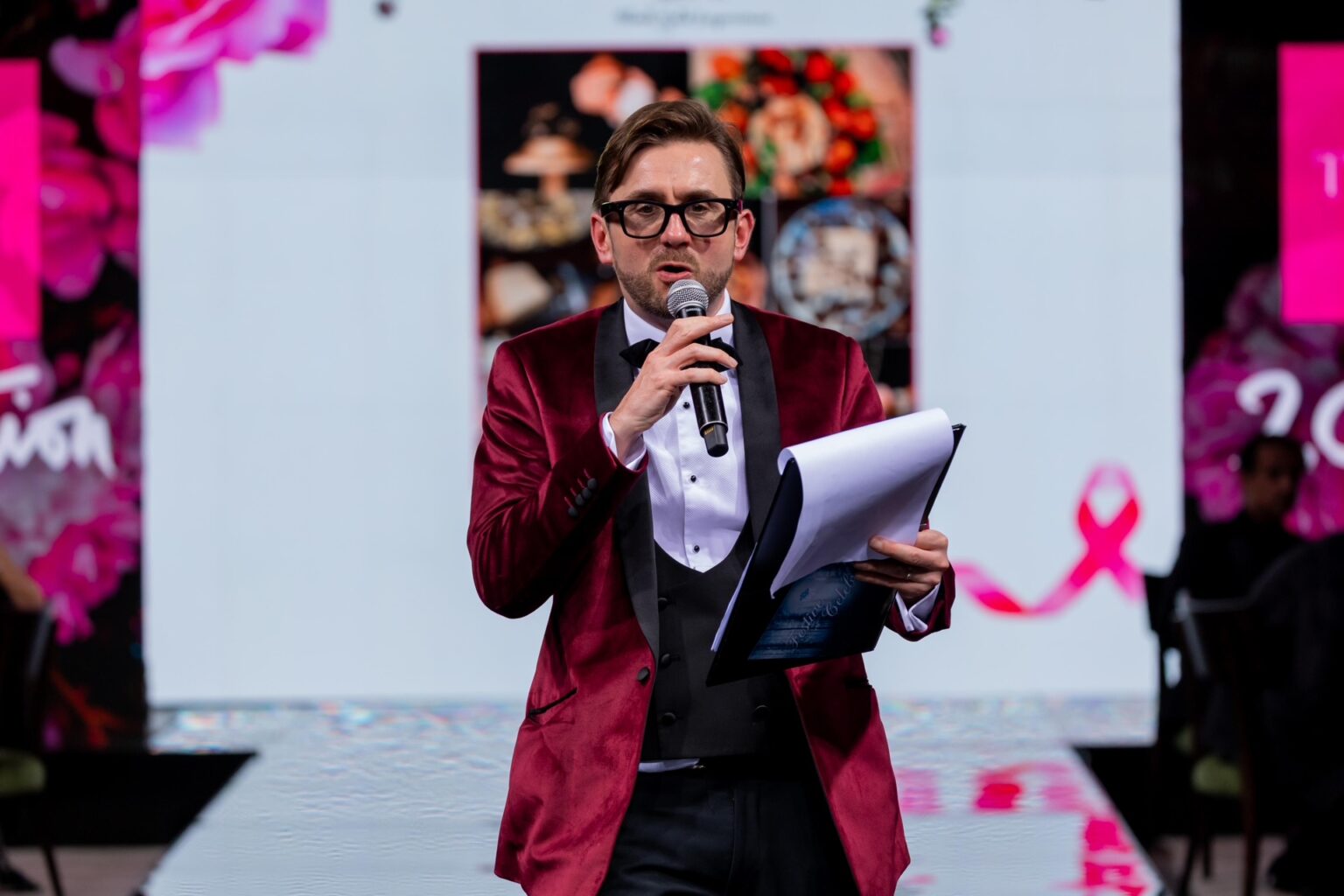 Charity auctioneer reading the next lot from his notes on stage at a charity ball