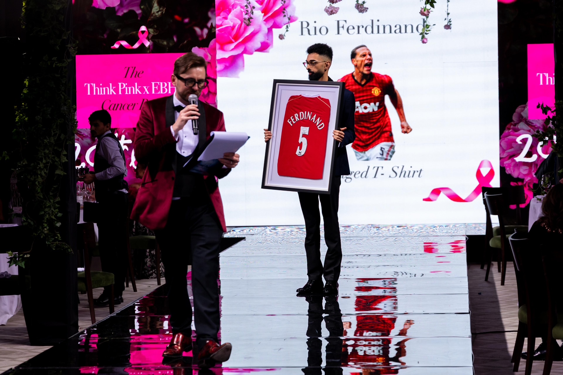 Auctioneer selling a framed signed Rio Ferdinand Manchester United shirt at a charity fundraising gala
