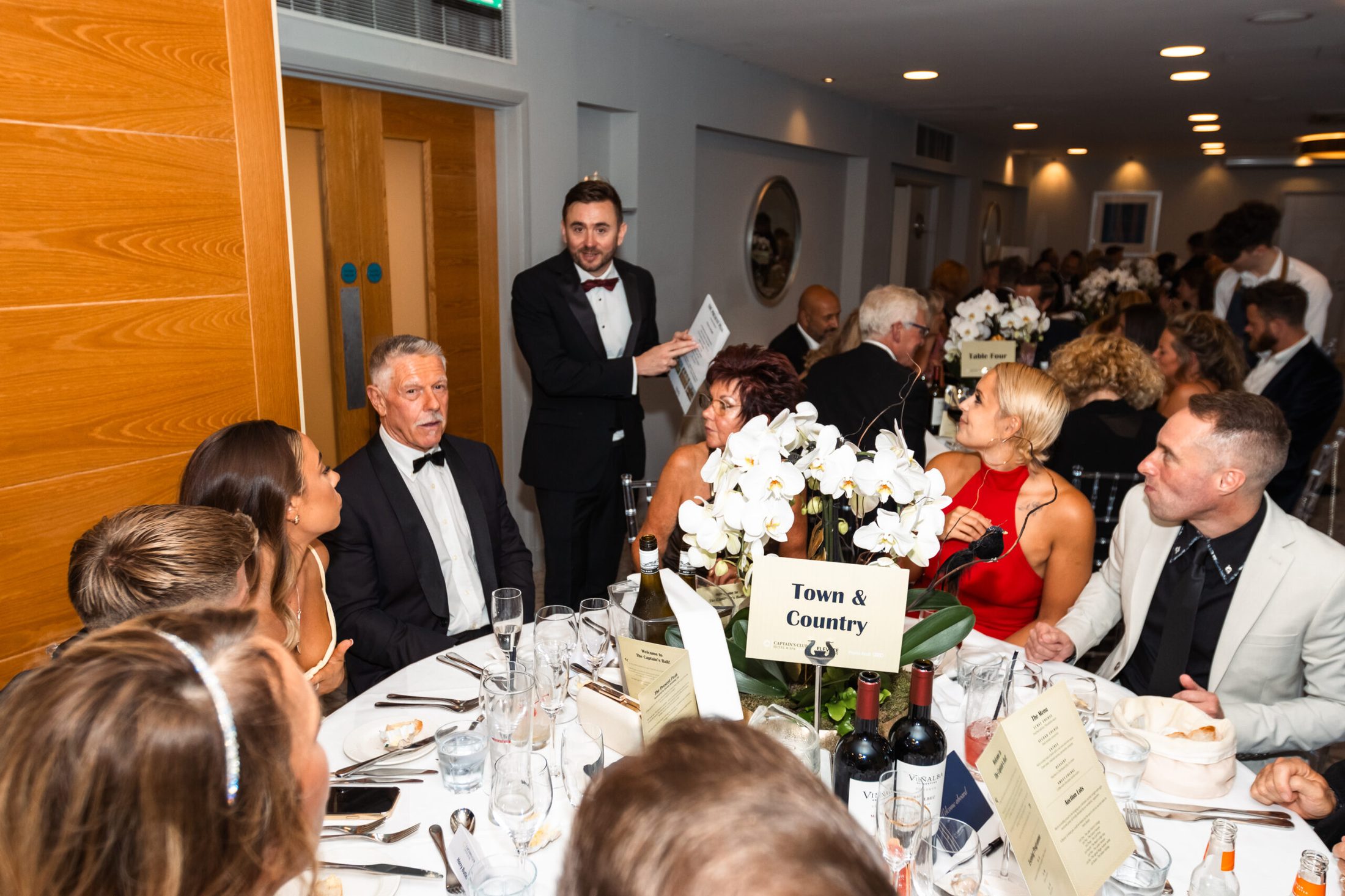 Charity auctioneer and event host Kevin Durham at a fundraising gala, pictured with guests during the evening's programme.