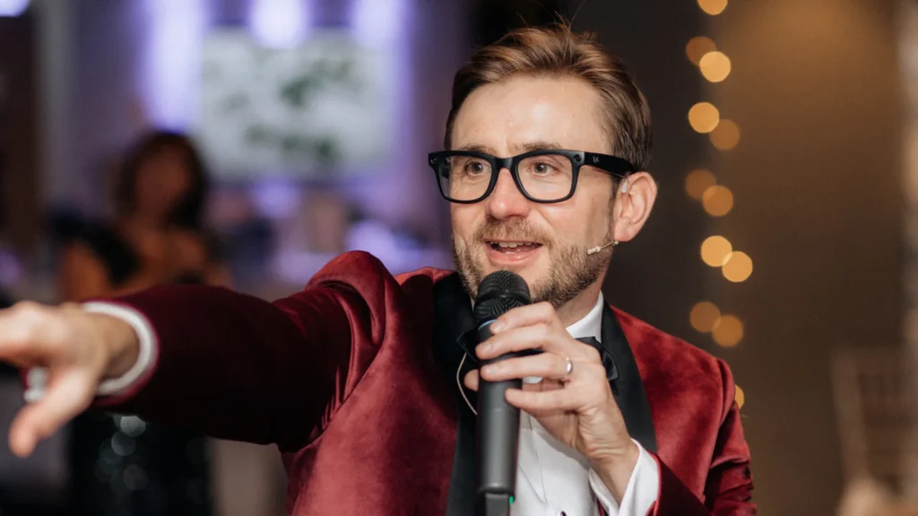 Kevin Durham speaking into a microphone and gesturing while running a live auction at the Jigsaw charity gala Kevin Durham speaking into a microphone and gesturing while running a live auction at the Jigsaw charity gala