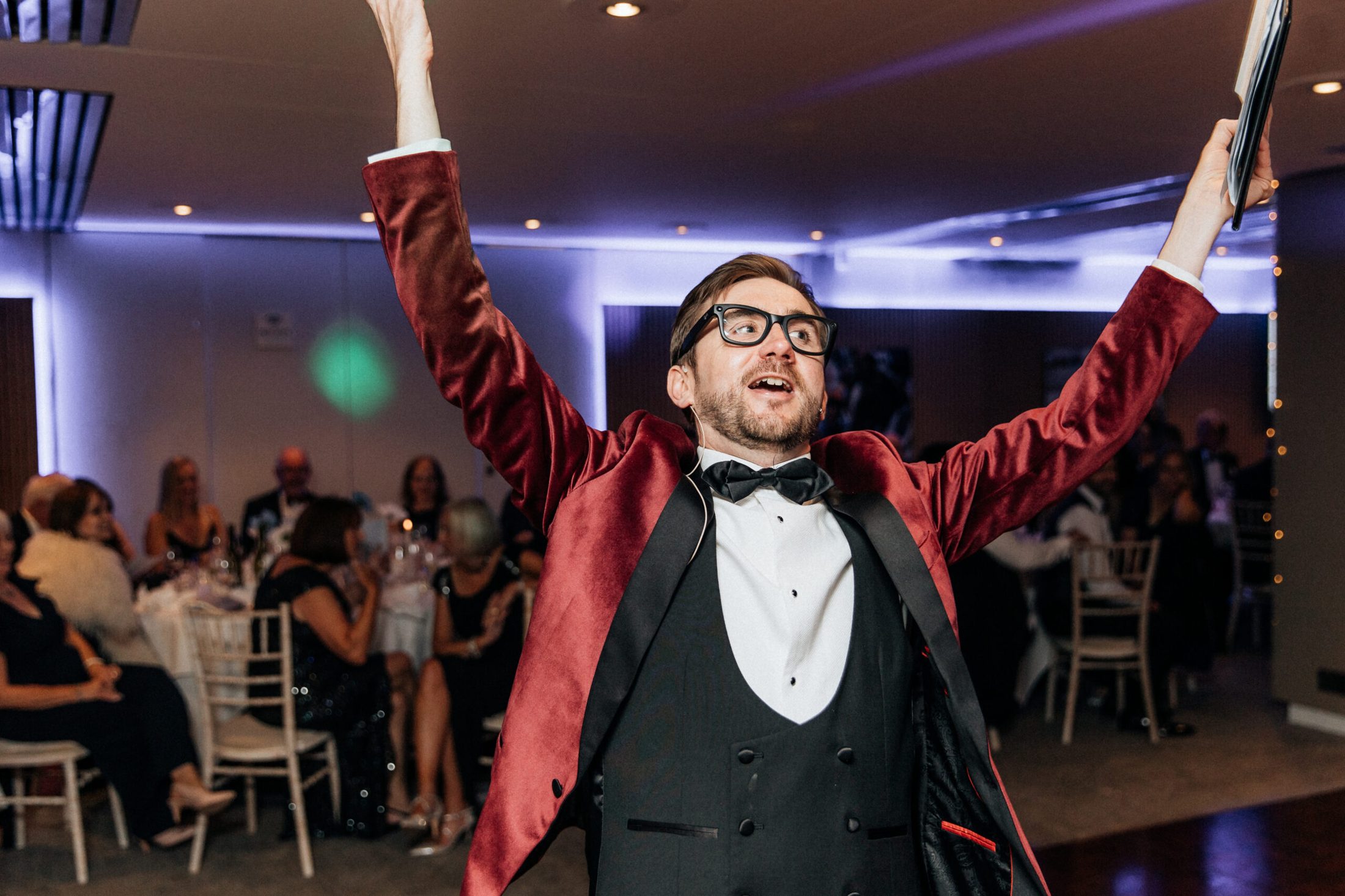Charity auctioneer Kevin Durham running the live auction at Jigsaw Trust's charity gala, addressing guests with a wireless microphone from the floor.
