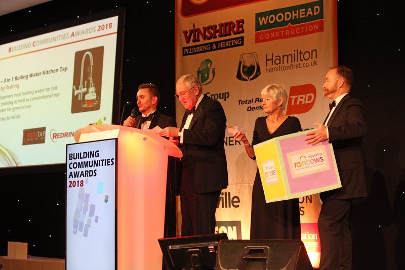 Kevin Durham presenting an award on stage at a business awards ceremony