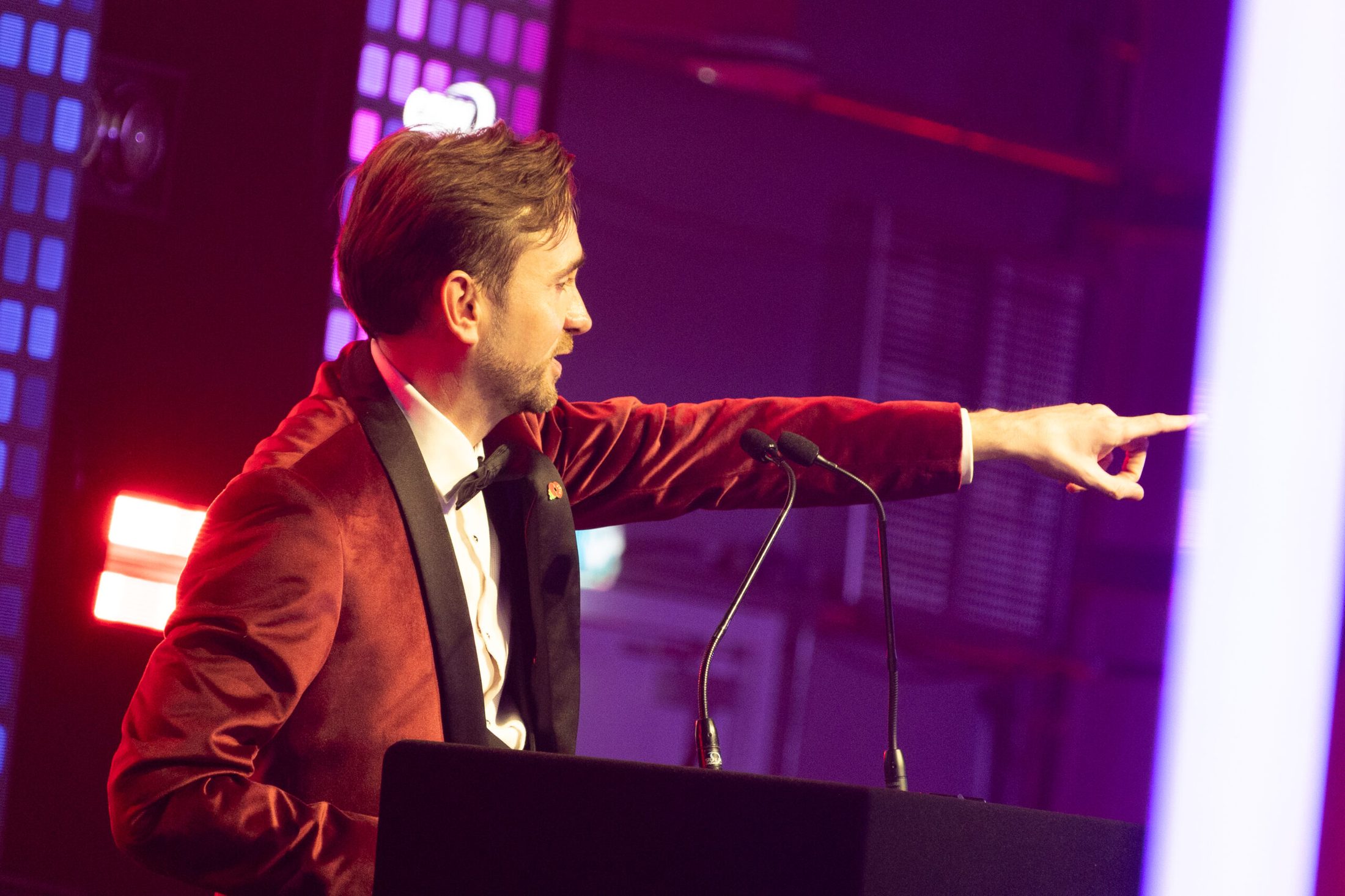A professional charity auctioneer working the floor during a live auction.
