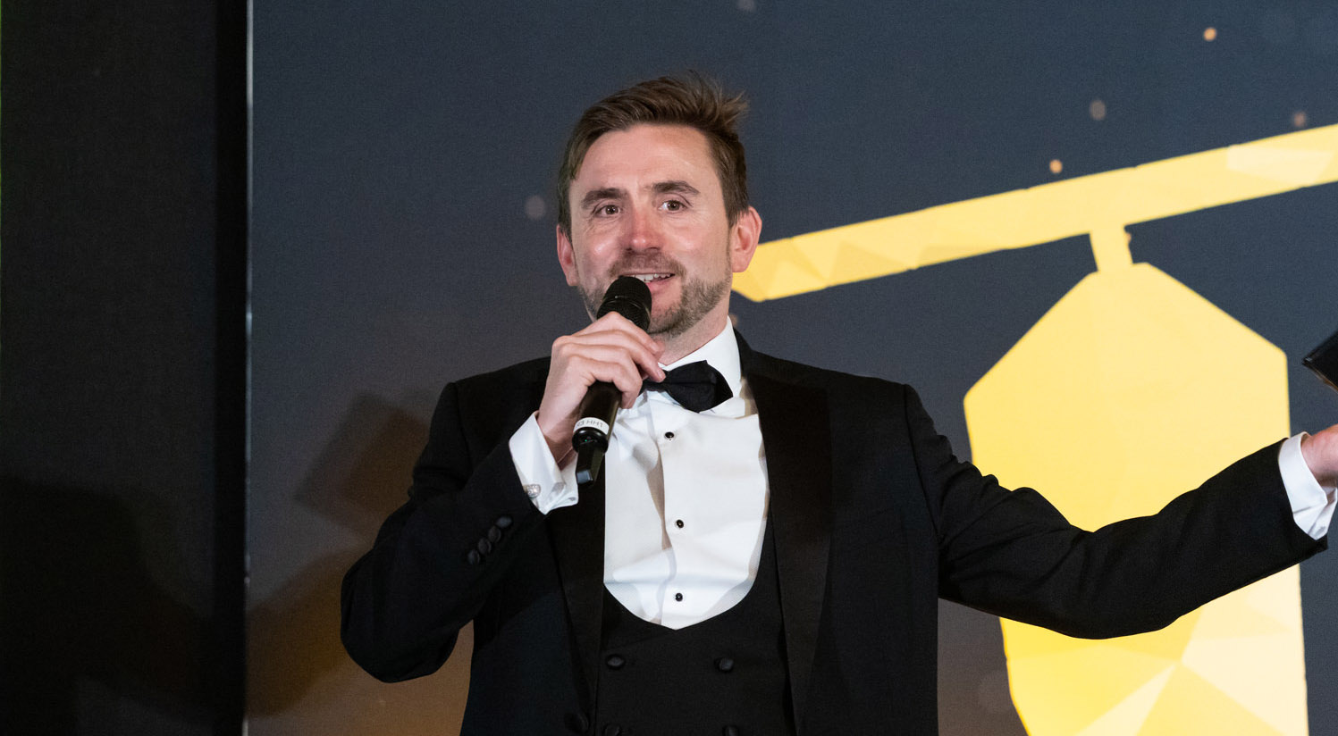 Kevin Durham speaking into a microphone while hosting a live event